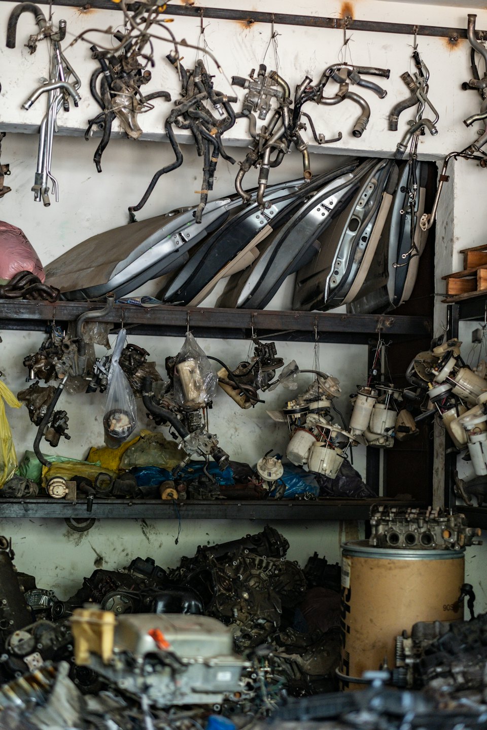 Used car parts organized on metal shelves in a workshop.