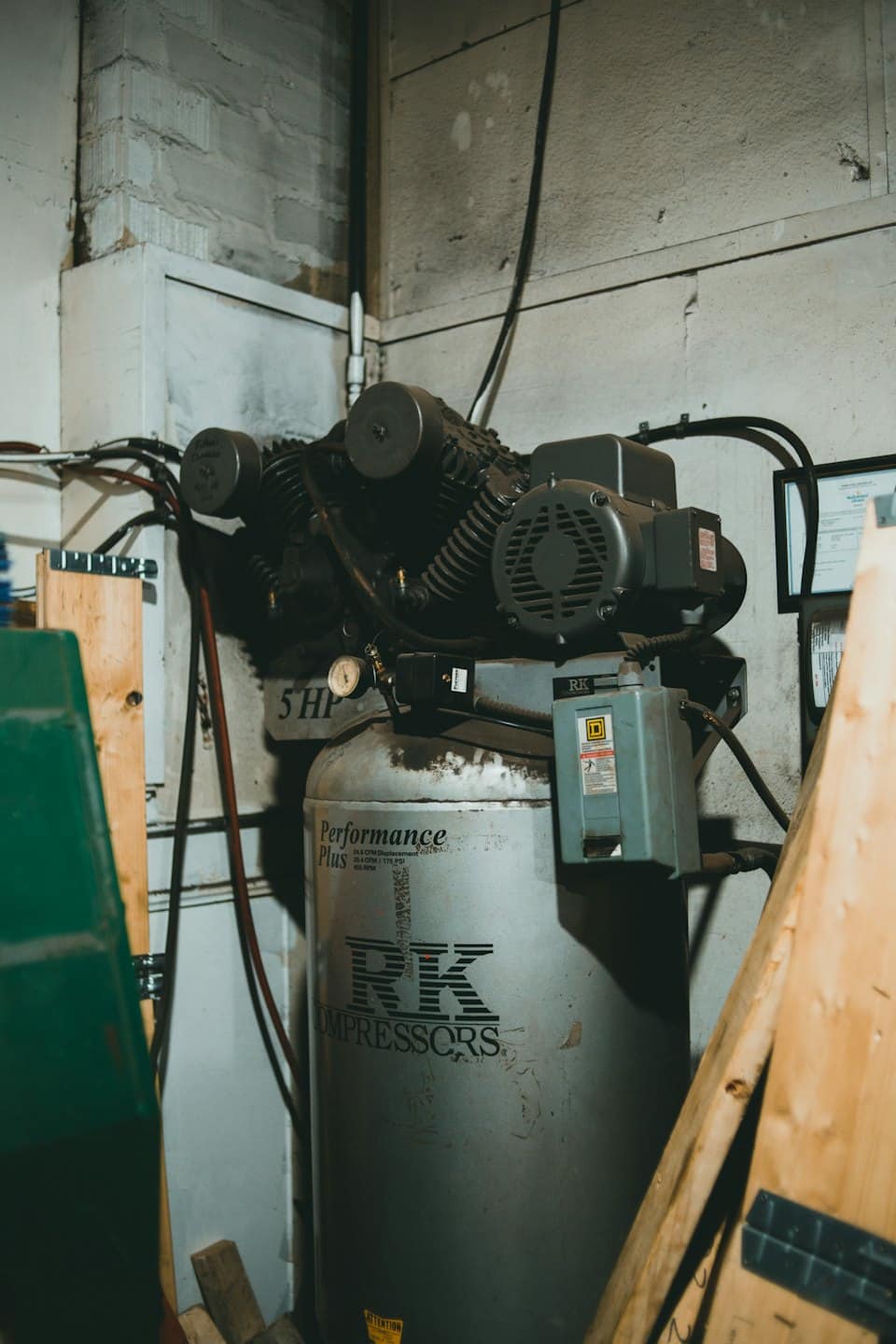 An old grey industrial air compressor with pipes and wires.